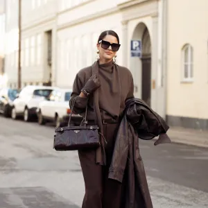 COPENHAGEN, DENMARK - DECEMBER 03: Gili Biegun wears brown tailored trousers, Brown knit with scarf by Massimo Dutti, Celine sunglasses, oversized long Brown leather coat by Herskind, Prada Brown bag, Strathberry Brown leather gloves on December 03, 2024 in Copenhagen, Denmark. (Photo by Raimonda Kulikauskiene/Getty Images)