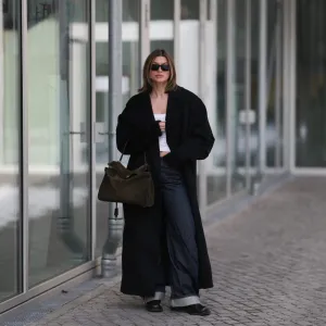 BERLIN, GERMANY - FEBRUARY 19: Sophia Geiss is seen wearing an oversized Bondi black coat layered over a fitted Black Palms top, styled with Acne Studios jeans in a relaxed, straight-leg silhouette. She completes the look with Alohas shoes, adding a clean and modern finish. Accessories include oversized Prada shades with bold frames and a Balenciaga Rodeo suede bag on February 19, 2026 in Berlin, Germany. (Photo by Jeremy Moeller/Getty Images)