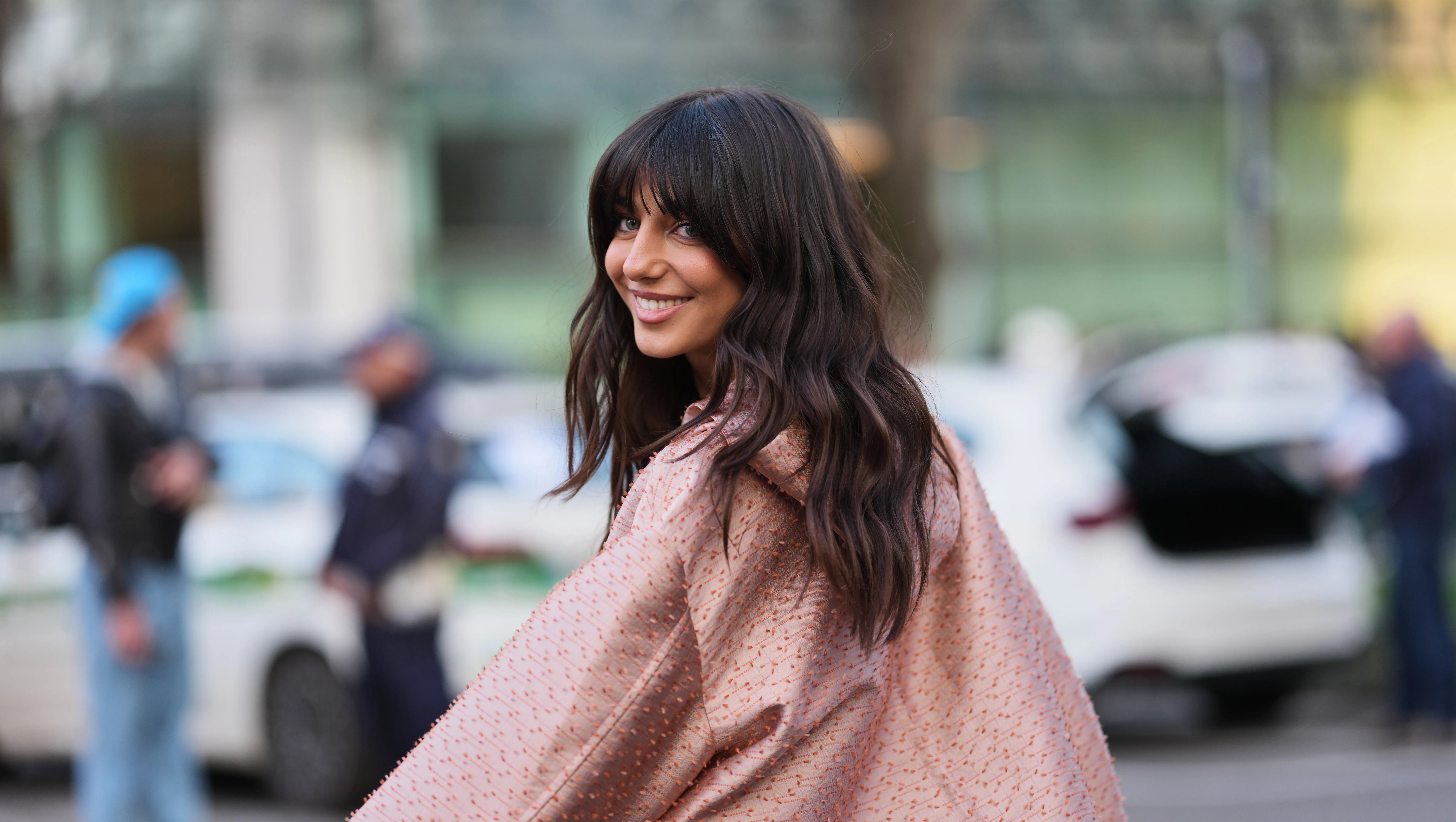 MILAN, ITALY - FEBRUARY 26: A guest wears dark brown hair with bangs, a light pink with red embroidered textured pattern / button front jacket with a coral pink trim, matching light pink with red textured pattern micro shorts, outside Emporio Armani, during Milan Fashion Week - Womenswear Fall/Winter 2026/2027, on February 26, 2026 in Milan, Italy (Photo by Edward Berthelot/Getty Images)