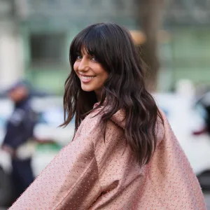 MILAN, ITALY - FEBRUARY 26: A guest wears dark brown hair with bangs, a light pink with red embroidered textured pattern / button front jacket with a coral pink trim, matching light pink with red textured pattern micro shorts, outside Emporio Armani, during Milan Fashion Week - Womenswear Fall/Winter 2026/2027, on February 26, 2026 in Milan, Italy (Photo by Edward Berthelot/Getty Images)