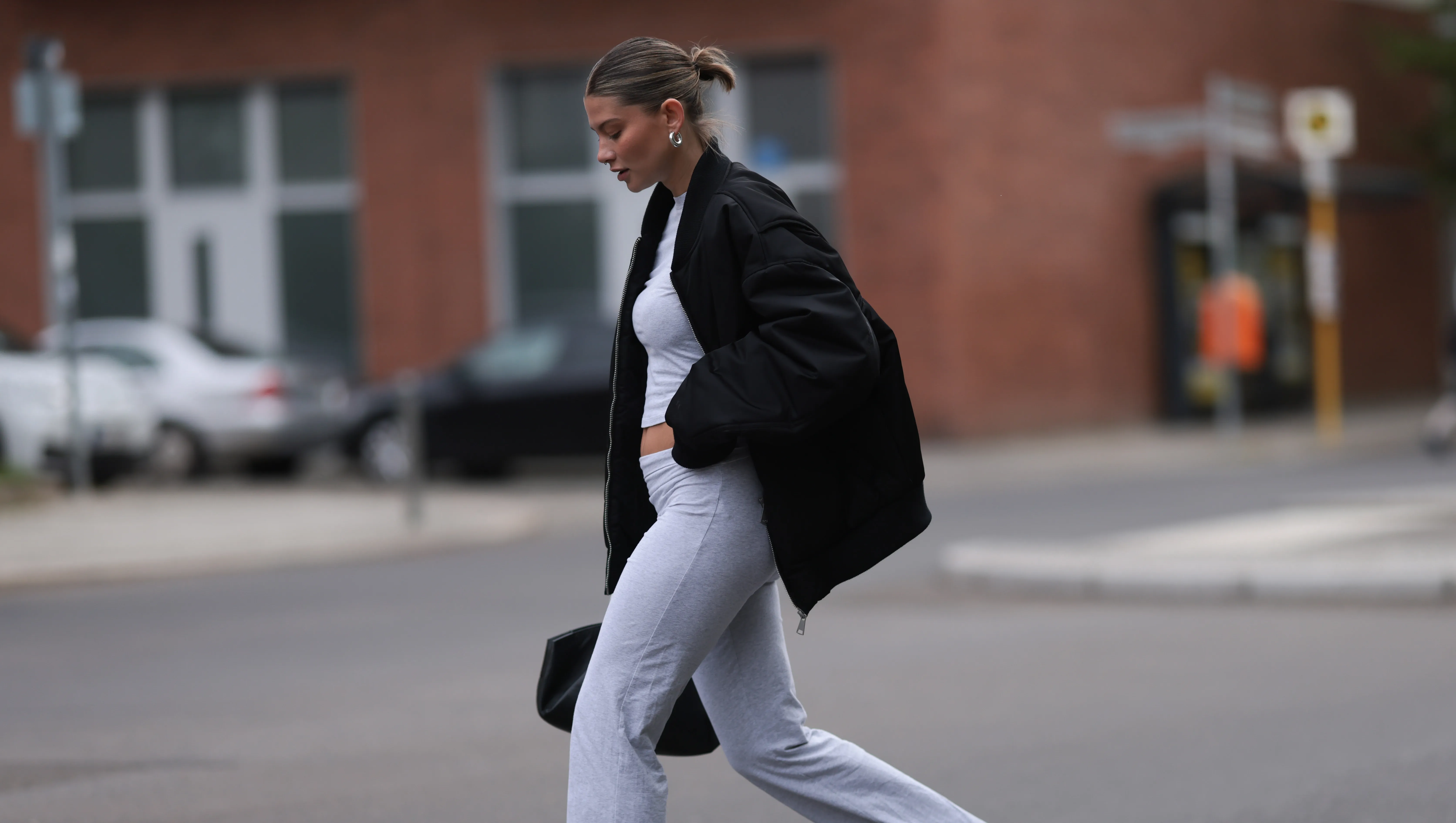 BERLIN, GERMANY - APRIL 22: Sophia Geiss seen wearing silver earrings, light grey cropped top, matching light grey wide leg pants, black oversized bomber jacket, black leather bag, white headphones and Crocs getaway platform flip in acidity, on April 22, 2024 in Berlin, Germany. (Photo by Jeremy Moeller/Getty Images)