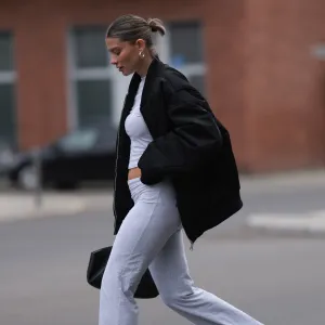 BERLIN, GERMANY - APRIL 22: Sophia Geiss seen wearing silver earrings, light grey cropped top, matching light grey wide leg pants, black oversized bomber jacket, black leather bag, white headphones and Crocs getaway platform flip in acidity, on April 22, 2024 in Berlin, Germany. (Photo by Jeremy Moeller/Getty Images)
