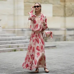 MUNICH, GERMANY - MAY 29: Marlies Pia Pfeifhofer is seen wearing a light beige silk chiffon long sleeve maxi dress with red and pink prints of feathers and flowers, drawstring waist, deep V-neck with front tie and smocking details on the collar and cuffs from FENDI, a natural-colored Baguette canvas bag with coral bandana embroidery, small fringes on the flap, calfskin leather straps, golden hardware and logo detail as well as an additional golden chain metal charm with marine-inspired pendants and a red, pink and white bandana charm with golden logo clip from FENDI, a pair of chocolate brown leather gladiator sandals with a braided leather toe strap and one main strap from Alex Rivière x Manebi, a Louis Tortoise Brown sunglasses with slim and oval shape from Corlin, a gold-colored metal and brown nappa leather Forever Fendi necklace with shell-shaped pendants from FENDI, a brown leather Tank Louis watch with yellow gold rectangular watch case from Cartier, a silver diamond ring on May 29, 2025 in Munich, Germany. (Photo by Moritz Scholz/Getty Images)
