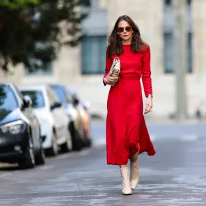 PARIS, FRANCE - APRIL 08: Therese Hellström wears sunglasses, a red midi long dress with sleeves, a Chanel bag, beige square toe high heels shiny boots, on April 08, 2021 in Paris, France. (Photo by Edward Berthelot/Getty Images)