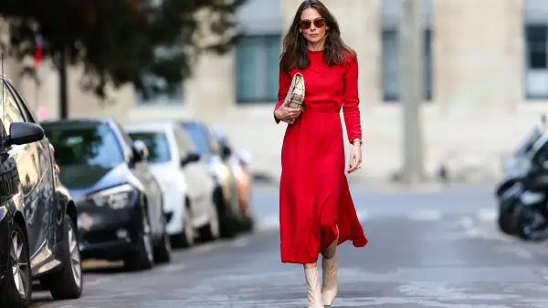PARIS, FRANCE - APRIL 08: Therese Hellström wears sunglasses, a red midi long dress with sleeves, a Chanel bag, beige square toe high heels shiny boots, on April 08, 2021 in Paris, France. (Photo by Edward Berthelot/Getty Images)