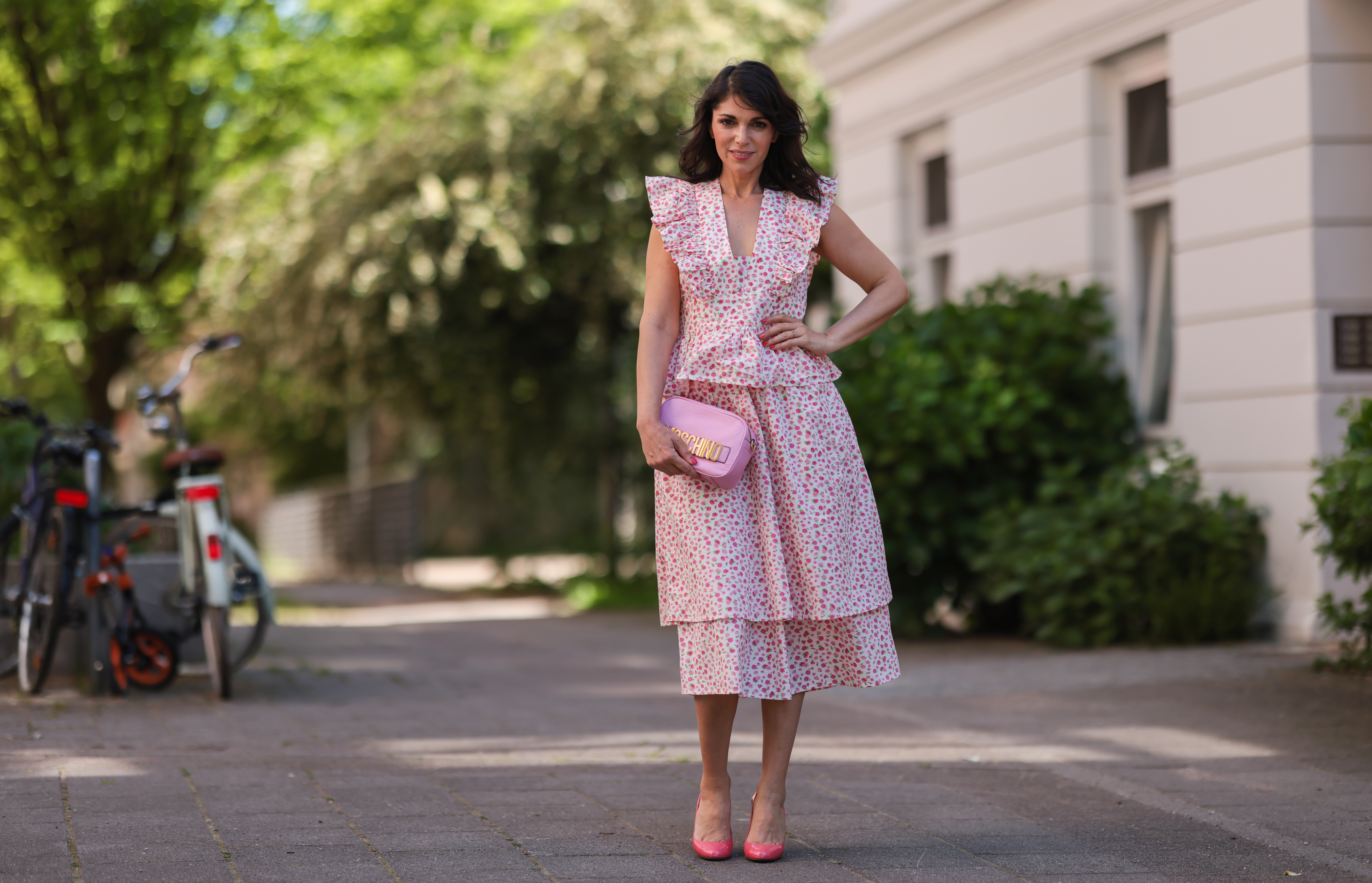 Anna Wolfers wearing white and pink ruffle dress via Goldig Shop, pink Moschino clutch and pink heels on May 31, 2021 in Hamburg, Germany.