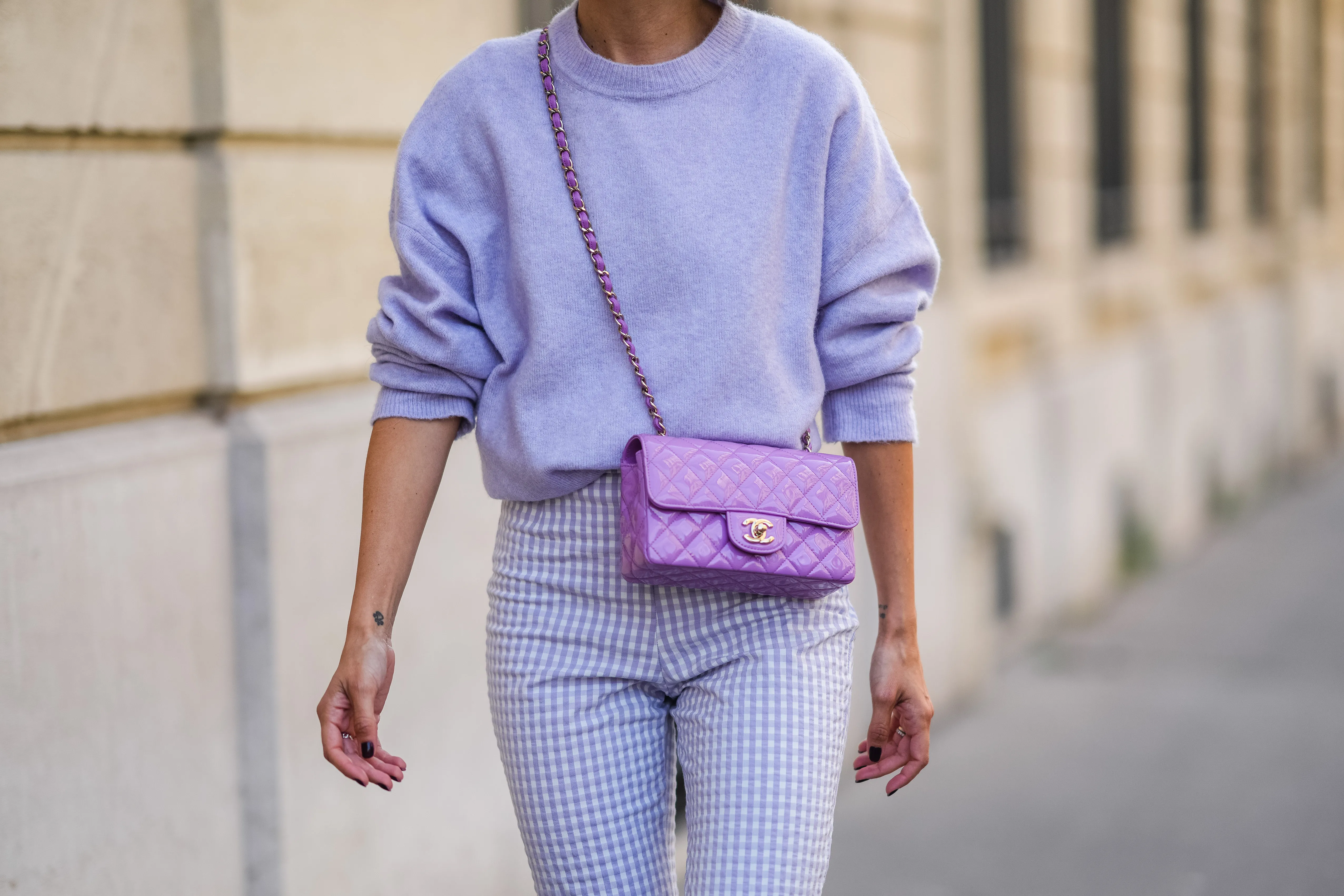 Alexandra Pereira wears a pale purple fluffy wool pullover, pale purple and white checkered pattern large pants, a purple shiny quilted leather Chanel crossbody bag, a silver ring, on September 16, 2021 in Paris, France.