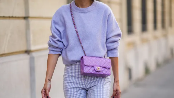Alexandra Pereira wears a pale purple fluffy wool pullover, pale purple and white checkered pattern large pants, a purple shiny quilted leather Chanel crossbody bag, a silver ring, on September 16, 2021 in Paris, France.