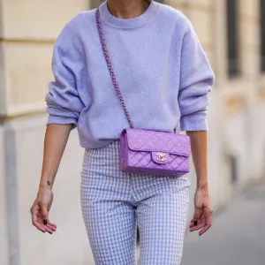 Alexandra Pereira wears a pale purple fluffy wool pullover, pale purple and white checkered pattern large pants, a purple shiny quilted leather Chanel crossbody bag, a silver ring, on September 16, 2021 in Paris, France.