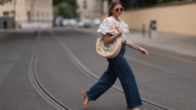 Aline Kaplan wearing Baum & Pferdgarten wide leg blue denim pants, & other stories white flower pattern cropped blouse and orange summer heels and Mango orange black shades on June 06, 2023 in Berlin, Germany.