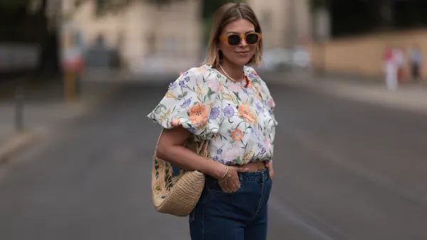 Aline Kaplan wearing Baum & Pferdgarten wide leg blue denim pants, & other stories white flower pattern cropped blouse and orange summer heels and Mango orange black shades on June 06, 2023 in Berlin, Germany.