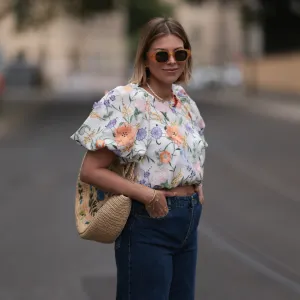 Aline Kaplan wearing Baum & Pferdgarten wide leg blue denim pants, & other stories white flower pattern cropped blouse and orange summer heels and Mango orange black shades on June 06, 2023 in Berlin, Germany.