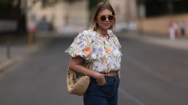 Aline Kaplan wearing Baum & Pferdgarten wide leg blue denim pants, & other stories white flower pattern cropped blouse and orange summer heels and Mango orange black shades on June 06, 2023 in Berlin, Germany.