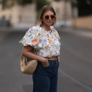 Aline Kaplan wearing Baum & Pferdgarten wide leg blue denim pants, & other stories white flower pattern cropped blouse and orange summer heels and Mango orange black shades on June 06, 2023 in Berlin, Germany.