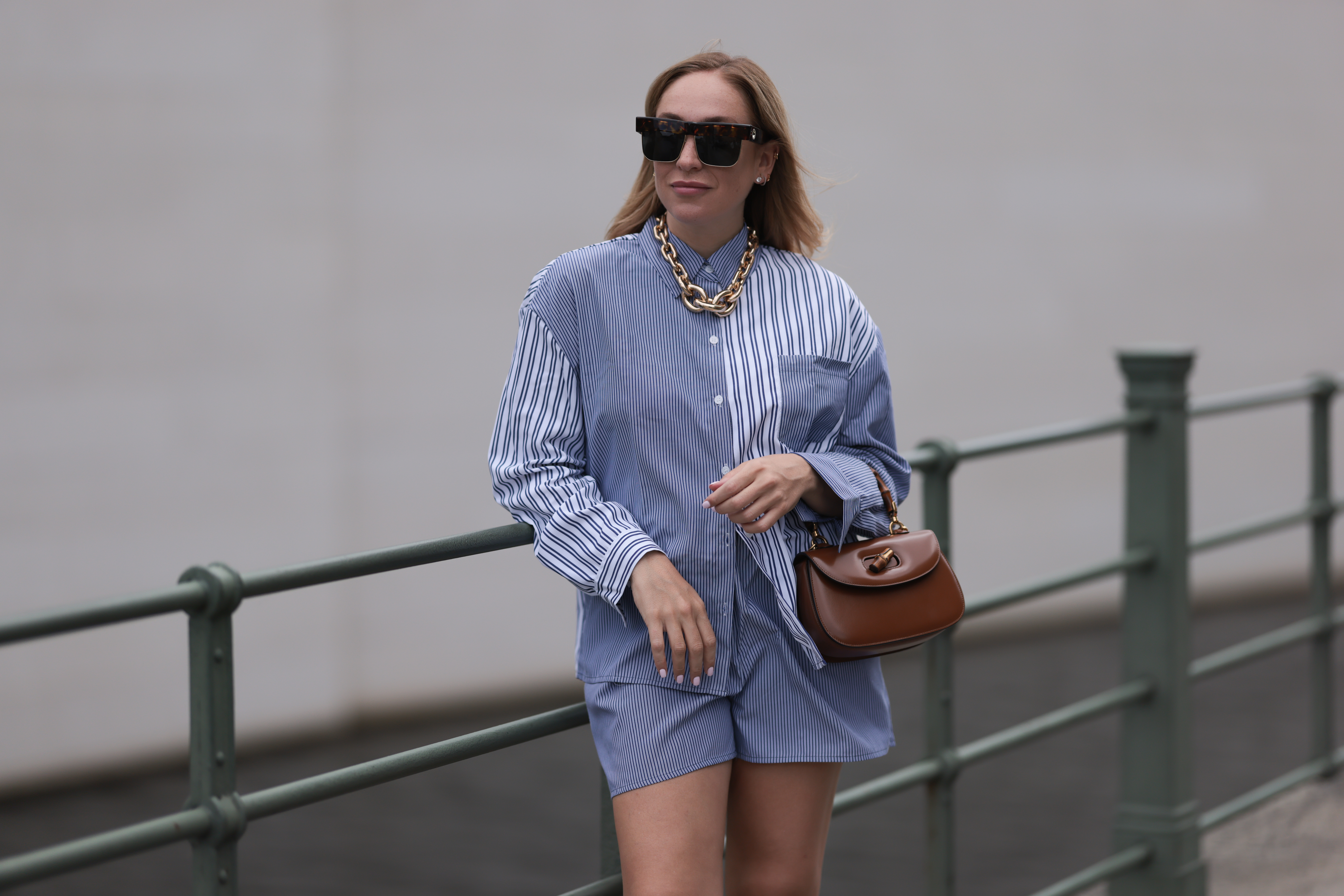 BERLIN, GERMANY - JUNE 28: Sonia Lyson wearing Gold Zara statement link chain, Storets matching two piece set includes a buttoned blue and white striped flannel and short, Linda Farrow brown big shades and Gucci bamboo brown leather wood bag on June 28, 2023 in Berlin, Germany. (Photo by Jeremy Moeller/Getty Images)
