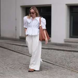 BERLIN, GERMANY - JUNE 11: Sonia Lyson is seen wearing sunglasses with havana frame from Givenchy, silver earrings, a golden necklace, a white blouse with puffed sleeves and ruffled details from Horror Vacui, cream-white wide linen pants from Zara, the “Low Key Hobo” bag in brown leather from Louis Vuitton and brown suede sandals from Hermès on June 11, 2024 in Berlin, Germany. (Photo by Jeremy Moeller/Getty Images)