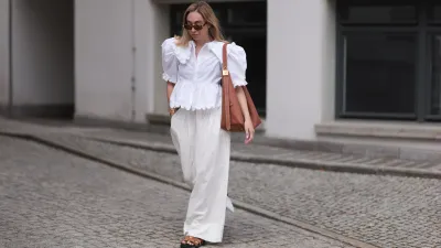 BERLIN, GERMANY - JUNE 11: Sonia Lyson is seen wearing sunglasses with havana frame from Givenchy, silver earrings, a golden necklace, a white blouse with puffed sleeves and ruffled details from Horror Vacui, cream-white wide linen pants from Zara, the “Low Key Hobo” bag in brown leather from Louis Vuitton and brown suede sandals from Hermès on June 11, 2024 in Berlin, Germany. (Photo by Jeremy Moeller/Getty Images)