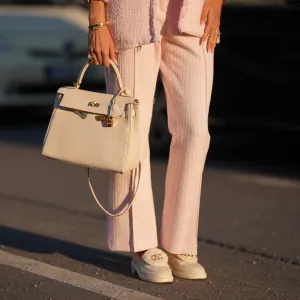 Shanice Messina is seen wearing a pink cropped marlene bouclé pants from Zara, a pink bouclé box jacket from Zara, a pair of leather moccasins in ivory with golden logo detail from Chanel, a white Kelly bag with golden details from Hermès, stacked rings with gemstones from Pomellato, a golden Just en Clou and LOVE bracelet from Cartier on May 11, 2025 in Munich, Germany.