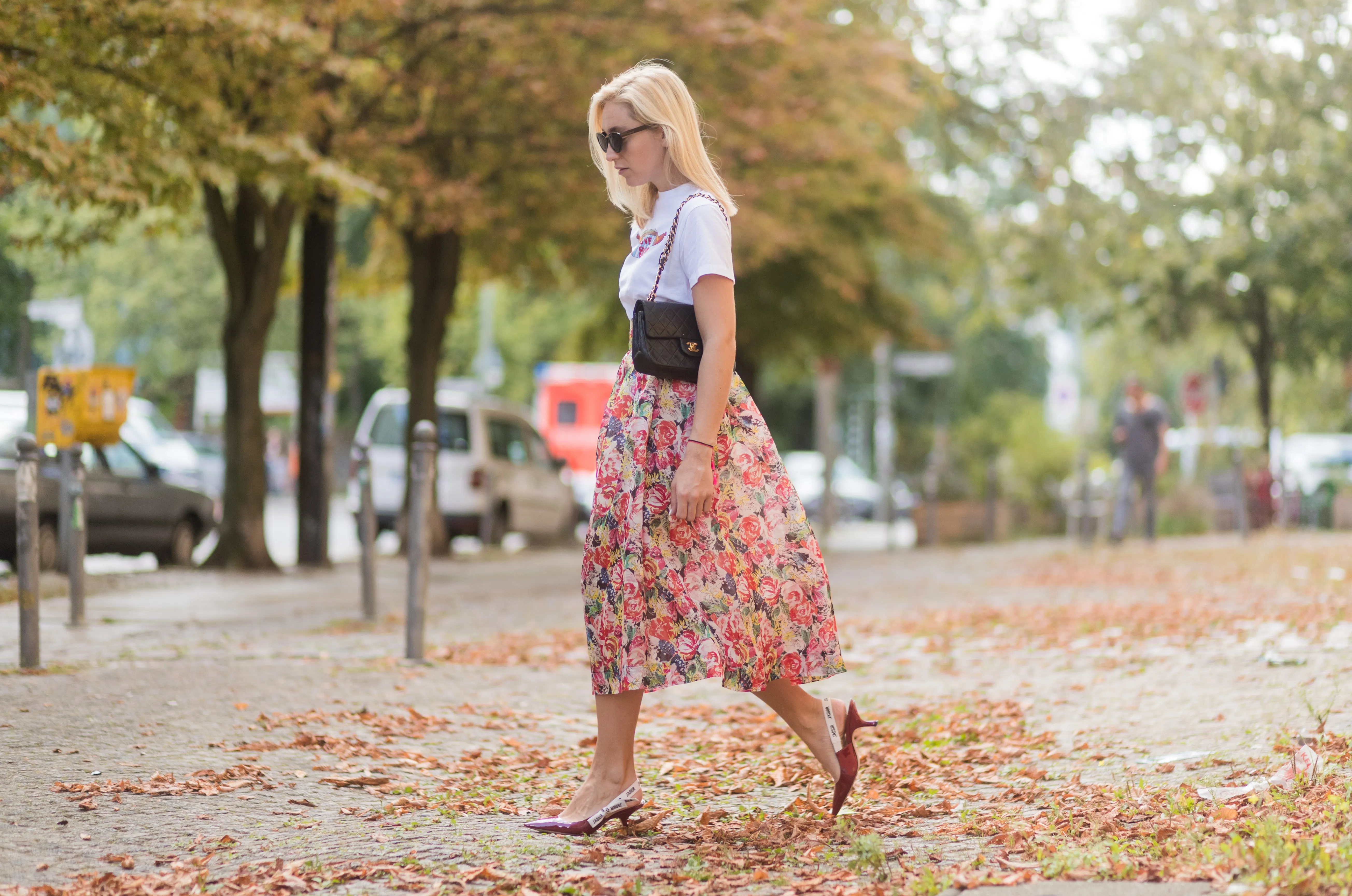 Sonia Lyson wearing a midi skirt with floral print Ganni, a white T-shirt with the print Love Dog from Ganni, a black Chanel vintage bag, vintage sunglasses, red Dior shoes on August 28, 2017 in Berlin, Germany.
