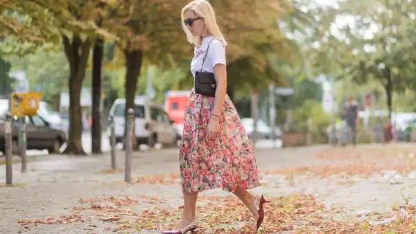 Sonia Lyson wearing a midi skirt with floral print Ganni, a white T-shirt with the print Love Dog from Ganni, a black Chanel vintage bag, vintage sunglasses, red Dior shoes on August 28, 2017 in Berlin, Germany.