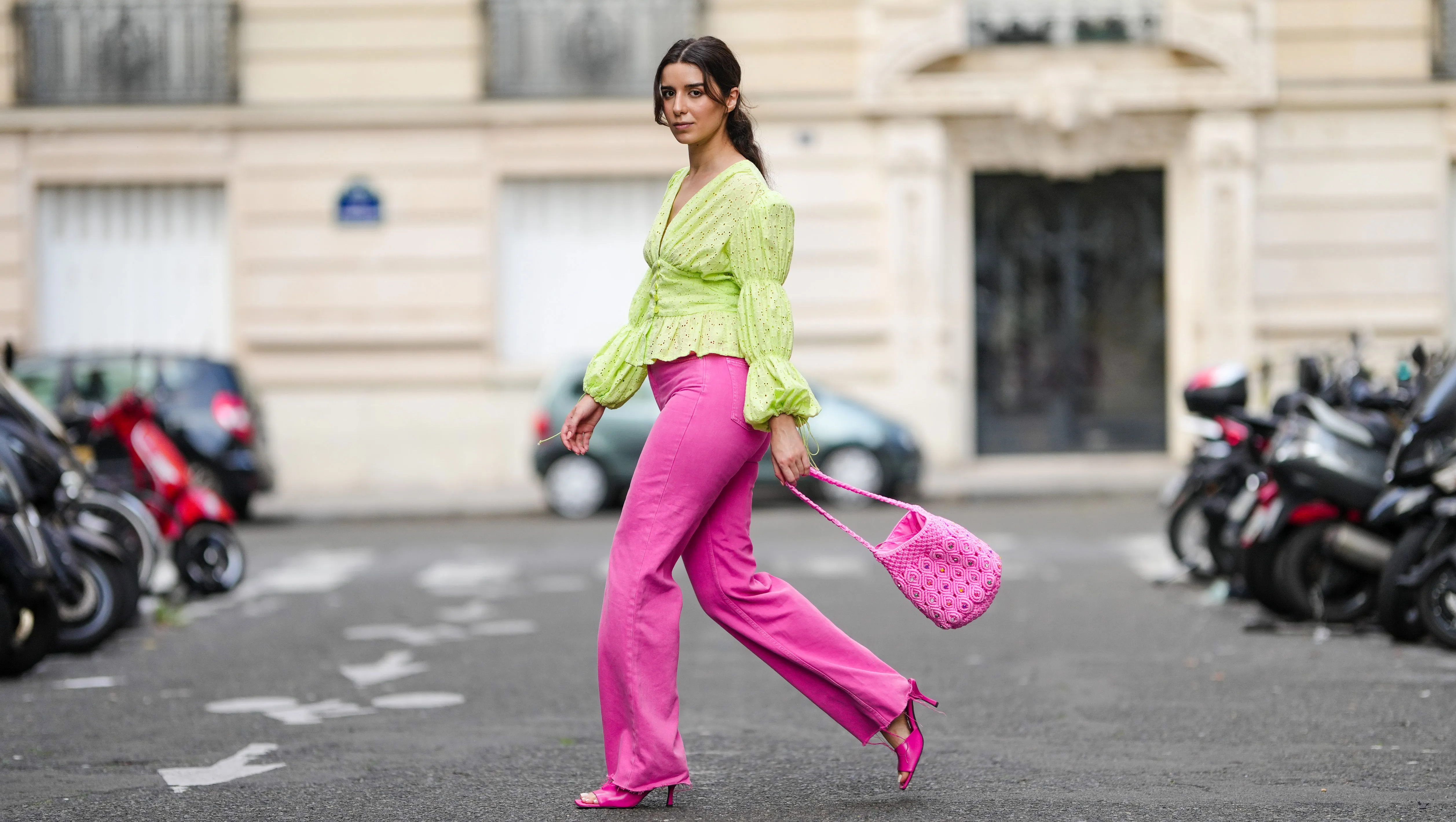 PARIS, FRANCE - AUGUST 12: Ketevan Giorgadze @katie.one wears neon pink high-waisted wide leg denim jeans from Zara, a neon green ruffle embroidered low-neck v-neck blouse with puff sleeves from Botrois, hot pink mules shoes from Zara, a hot pink knit bucket bag with stones from Manoush, on August 12, 2021 in Paris, France. (Photo by Edward Berthelot/Getty Images)