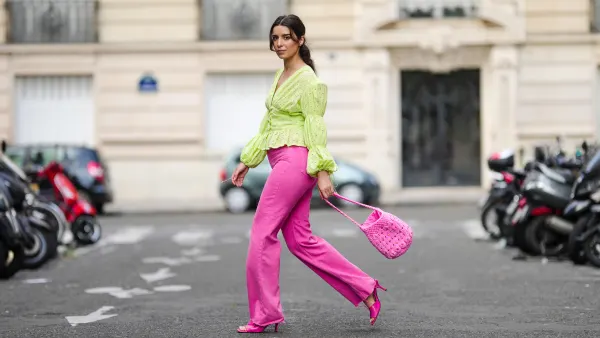 PARIS, FRANCE - AUGUST 12: Ketevan Giorgadze @katie.one wears neon pink high-waisted wide leg denim jeans from Zara, a neon green ruffle embroidered low-neck v-neck blouse with puff sleeves from Botrois, hot pink mules shoes from Zara, a hot pink knit bucket bag with stones from Manoush, on August 12, 2021 in Paris, France. (Photo by Edward Berthelot/Getty Images)