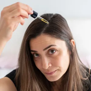 Woman Applying Hair Serum To Her Hair
