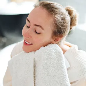 Woman wiping face in bathroom - stock photo