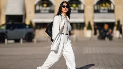 PARIS, FRANCE - FEBRUARY 27: Xiayan wears black Bottega Veneta sunglasses, silver earrings, a silver chain necklace, a white V-neck silk gown, a white long oversized Sundarbay blazer jacket with white suit Sundarbay matching pants, a black shiny leather belt, white and beige with gold details Stellaluna sneakers, a black shiny leather Louis Vuitton monogram-embossed Coussin PM crossbody bag, on February 27, 2021 in Paris, France. (Photo by Edward Berthelot/Getty Images)