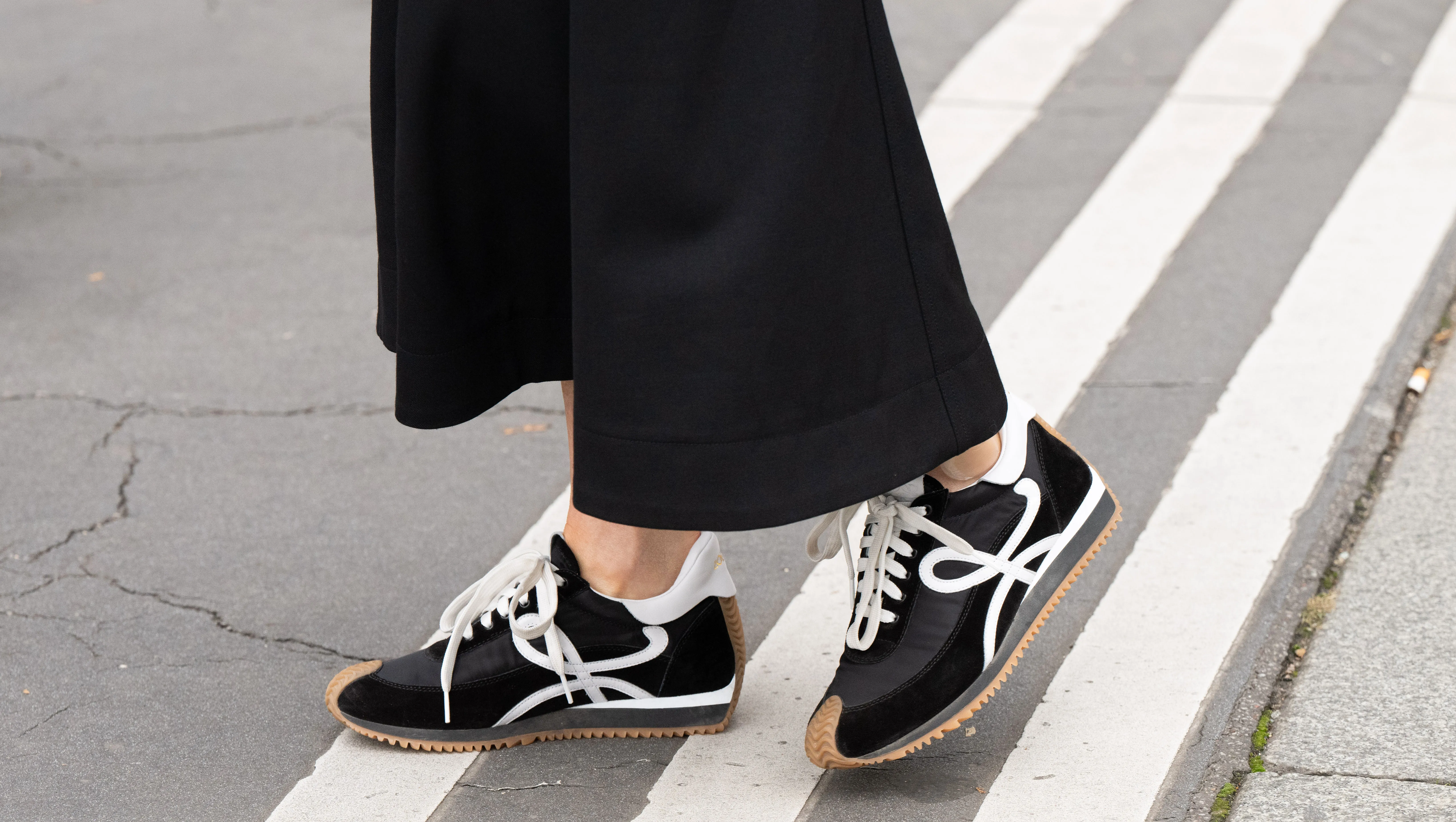 PARIS, FRANCE - SEPTEMBER 28: A guest wears Loewe trainers and wide leg black trousers outside the Hermes show during Womenswear Spring/Summer 2025 as part of Paris Fashion Week on September 28, 2024 in Paris, France. (Photo by Kirstin Sinclair/Getty Images)