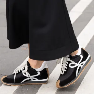 PARIS, FRANCE - SEPTEMBER 28: A guest wears Loewe trainers and wide leg black trousers outside the Hermes show during Womenswear Spring/Summer 2025 as part of Paris Fashion Week on September 28, 2024 in Paris, France. (Photo by Kirstin Sinclair/Getty Images)