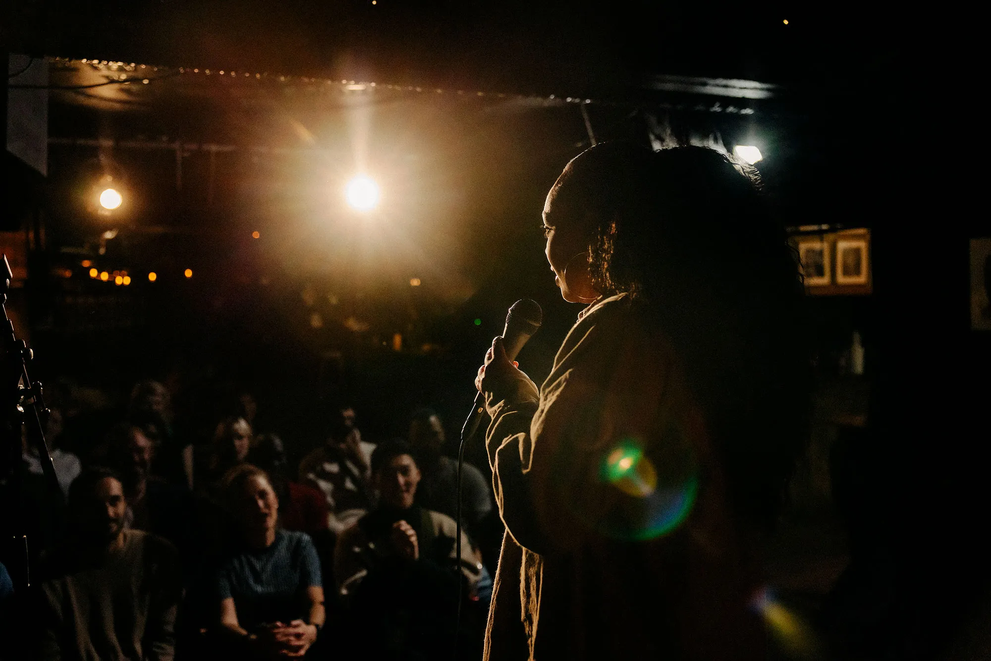 Young woman performing stand up comedy for multiracial audience