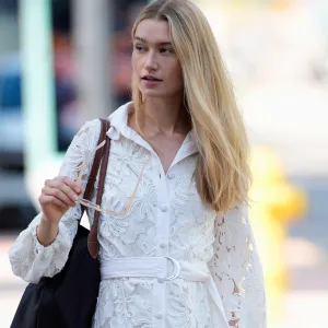 MIAMI, FLORIDA - OCTOBER 23: Maggie Krebs is seen wearing straight blonde hair, oversized light pink sunglasses, a Garota white lace long-sleeve belted mini dress, carrying a large black shoulder bag, and Dolce Vita beige knee-high boots outside Naeem Khan, during Miami Fashion Week on October 23, 2025 in Miami, Florida. (Photo by 305pics/Getty Images)