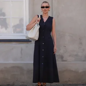 COPENHAGEN, DENMARK - AUGUST 6: Justyna Czerniak wears black sunglasses, gold earrings, black tailored vest midi dress, gold necklace, gold rings, cream DeMellier leather bag, black Alaia sheer mesh ballet flats, outside Lovechild 1979, during the Copenhagen Fashion Week Spring/Summer 2024-2025 on August 6, 2024 in Copenhagen, Denmark. (Photo by Edward Berthelot/Getty Images)