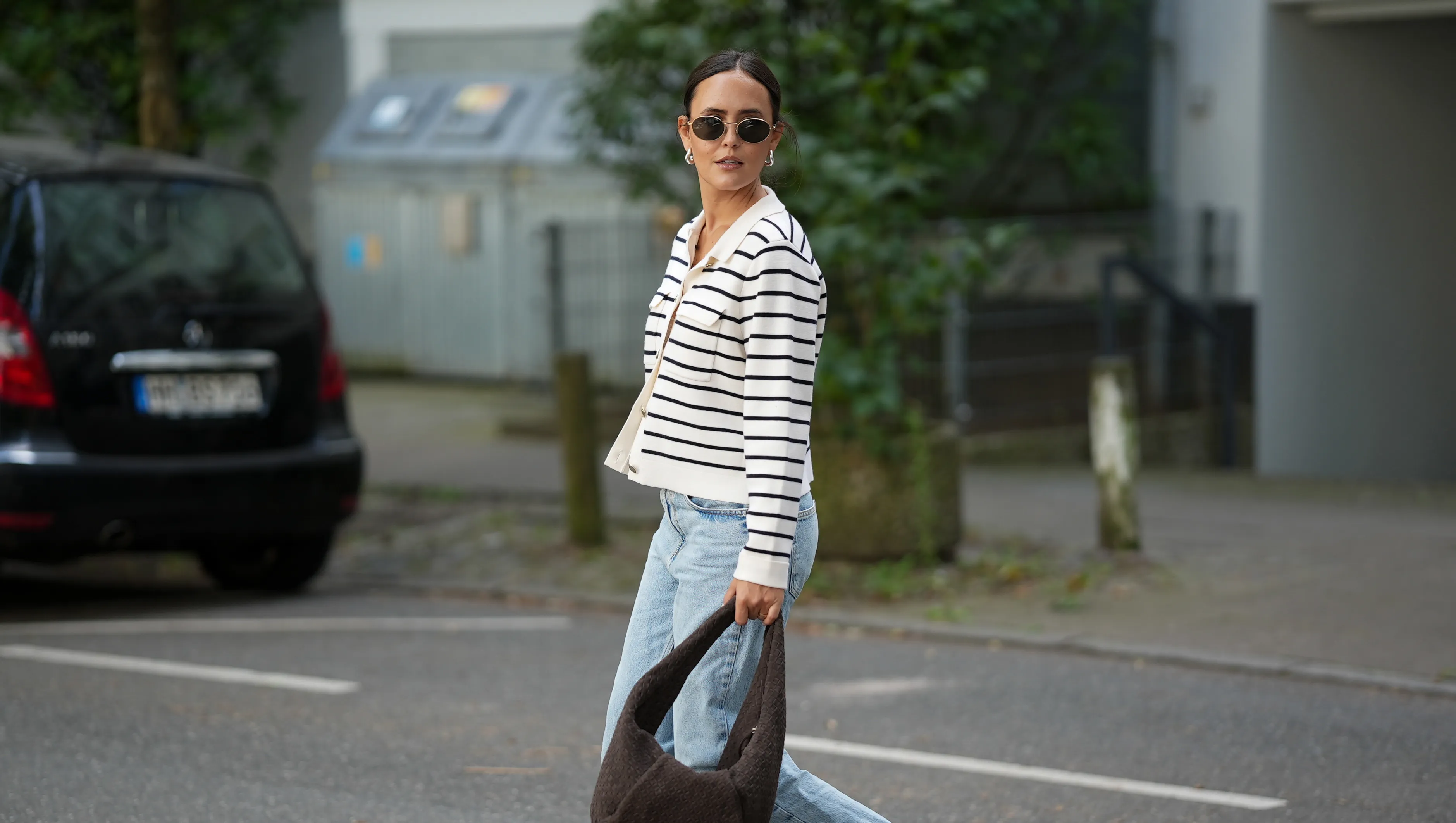 HAMBURG, GERMANY – AUGUST 17: Laura Noltemeyer is seen wearing a cream-and-navy striped knit cardigan with pearl buttons from Sézane; styled with light blue high-waisted straight-leg jeans with frayed hems from Zara; paired with taupe suede loafers from Birkenstock; is carrying a chocolate-brown woven leather shoulder bag from Les Visionnaires; accessorized with round metal-frame sunglasses from Persol and a delicate silver bracelet. Her hair is parted in the middle and styled in a sleek low ponytail on August 17, 2025 in Hamburg, Germany. (Photo by Moritz Scholz/Getty Images)