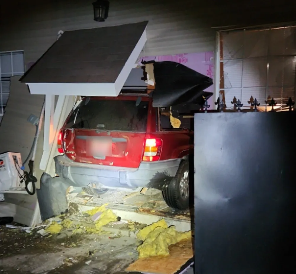 A photo shows a red SUV inside a mangled home