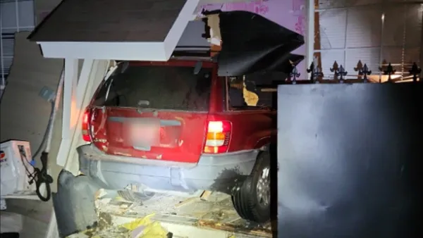 A photo shows a red SUV inside a mangled home