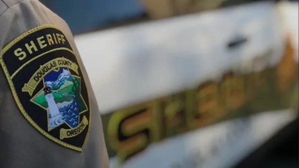 A Douglas County Sheriff's deputy stands near a patrol car