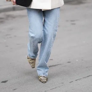 MUNICH, GERMANY - FEBRUARY 18: Oeznur Sinani alias Sinperi is seen wearing a cream colored and waist tailored double breasted blazer with structured shoulders, wide notch lapels, flap pockets and black button closure from Jacquemus; light blue high waisted straight leg denim jeans from TOTEME; tiger print pointed toe pumps with a slim heel from H&M; a "Chanel 25 Caviar" Handbag in a black quilted leather with gold hardware elements including the chain shoulder strap from Chanel on February 18, 2026 in Munich, Germany. (Photo by Moritz Scholz/Getty Images)