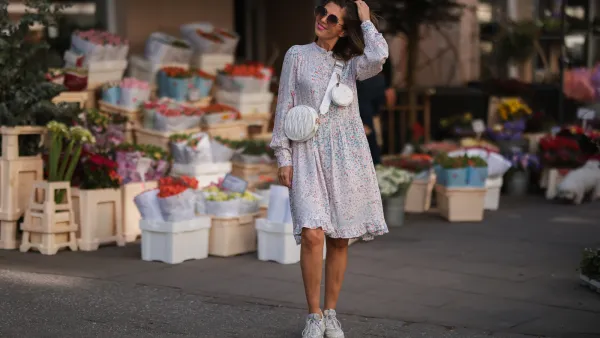 Anna Wolfers wearing brown shades, a pink floral midi dress and a white leather bag via goldigshop.de and white selected femme sneaker on March 25, 2022 in Hamburg, Germany.