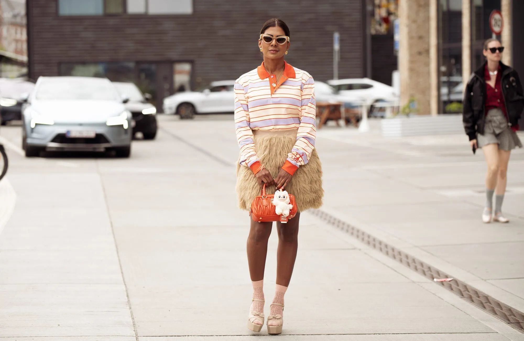 COPENHAGEN, DENMARK - AUGUST 07: Zufi Alexander wears beige mini skirt made of fur, orange MiuMiu bag with beige Labubu charm, purple, yellow and orange stripped long sleeve top, light pink socks, beige platform shoes during Copenhagen Fashion Week day four on August 07, 2025 in Copenhagen, Denmark. (Photo by Raimonda Kulikauskiene/Getty Images)