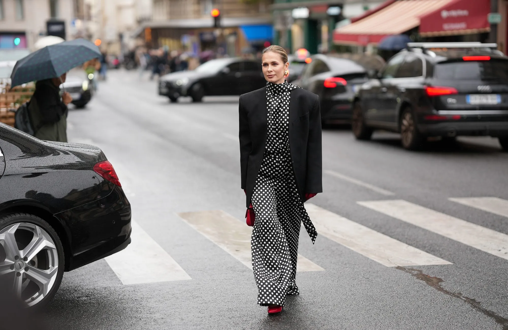 PARIS, FRANCE - OCTOBER 3: Iryna Thater is seen wearing full Nina Ricci look; a black oversized blazer jacket; a black and white polka dot high-neck blouse; a matching wide- leg polka dot trousers; red leather pointed-toe pumps shoes; gold-tone sculptural hoop earrings; red leather gloves; a red leather mini top-handle bag her blonde hair is styled a slicked-back pulled into a low bun outside the Nina Ricci Show during the Womenswear Spring Summer 2026 as part of Paris Fashion Week on October 3, 2025 in Paris, France. (Photo by Moritz Scholz/Getty Images)