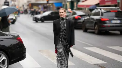 PARIS, FRANCE - OCTOBER 3: Iryna Thater is seen wearing full Nina Ricci look; a black oversized blazer jacket; a black and white polka dot high-neck blouse; a matching wide- leg polka dot trousers; red leather pointed-toe pumps shoes; gold-tone sculptural hoop earrings; red leather gloves; a red leather mini top-handle bag her blonde hair is styled a slicked-back pulled into a low bun outside the Nina Ricci Show during the Womenswear Spring Summer 2026 as part of Paris Fashion Week on October 3, 2025 in Paris, France. (Photo by Moritz Scholz/Getty Images)