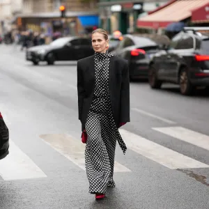PARIS, FRANCE - OCTOBER 3: Iryna Thater is seen wearing full Nina Ricci look; a black oversized blazer jacket; a black and white polka dot high-neck blouse; a matching wide- leg polka dot trousers; red leather pointed-toe pumps shoes; gold-tone sculptural hoop earrings; red leather gloves; a red leather mini top-handle bag her blonde hair is styled a slicked-back pulled into a low bun outside the Nina Ricci Show during the Womenswear Spring Summer 2026 as part of Paris Fashion Week on October 3, 2025 in Paris, France. (Photo by Moritz Scholz/Getty Images)