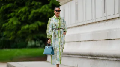 PARIS, FRANCE - MAY 12: Gabriella Berdugo wears sunglasses, earrings, a white blue and green checked long dress with long sleeves and floral print, a brown leather belt, a blue Kelly Hermes bag, pale pastel yellow mules / shoes with heart-shaped heels from Kat Maconie, during a street style fashion photo session, on May 12, 2024 in Paris, France. (Photo by Edward Berthelot/Getty Images)
