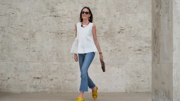 PARIS, FRANCE - MAY 02: Alba Garavito Torre wears black sunglasses, long straight brown hair with a center part, a white pleated peplum sleeveless blouse by Commense, and blue high-rise raw-hem denim jeans. A yellow clog sandal with floral detailing by AGL is worn, paired with a jean denim and brown mini Jackie handbag by Gucci. Accessories include a chunky necklace with colorful natural stones by Sempiterno Paris and gold jewelry. Full body shot, during a street style fashion photo session, on May 02, 2025 in Paris, France. (Photo by Edward Berthelot/Getty Images)