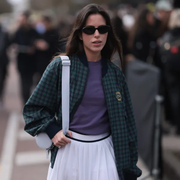 PARIS, FRANCE - MARCH 05: Nina Urgell Cloquell seen wearing a white tennis skirt, green and black checkered Lacoste jacket, purple shirt, black shades, black leather loafer, pink socks and a white Lacoste bag outside Lacoste Show during the Womenswear Fall/Winter 2024/2025 as part of Paris Fashion Week on March 05, 2024 in Paris, France. (Photo by Jeremy Moeller/Getty Images)