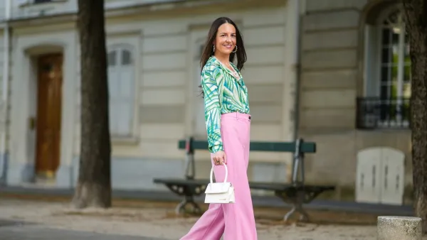 Alba Garavito Torre wears gold and pearls earrings, a white pearls necklace, a white with green tree leaf pattern shirt, pale pink flared suit pants, gold rings, a green ring, a pink ring, a gold Love Cartier bracelet, gold bracelets, a white matter leather Chiquito Medium Jacquemus handbag, dark green satin Manolo Blahnik pumps shoes, on May 23, 2021 in Paris, France.