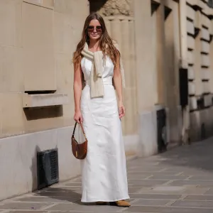 PARIS, FRANCE - APRIL 28: Diane Batoukina wears dark brown large squared sunglasses from Dior, a white square-neck / linen belted long dress, a white latte ribbed wool pullover knot at the shoulder, a camel brown shiny leather crocodile print pattern handbag from Ralph Lauren, brown suede block heels / pointed ankle boots , during a street style fashion photo session, on April 28, 2023 in Paris, France. (Photo by Edward Berthelot/Getty Images)