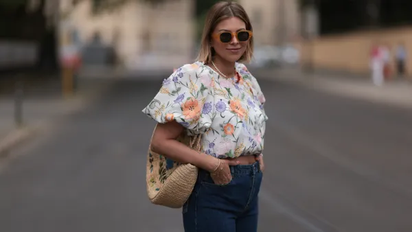 Aline Kaplan wearing Baum & Pferdgarten wide leg blue denim pants, & other stories white flower pattern cropped blouse and orange summer heels and Mango orange black shades on June 06, 2023 in Berlin, Germany.